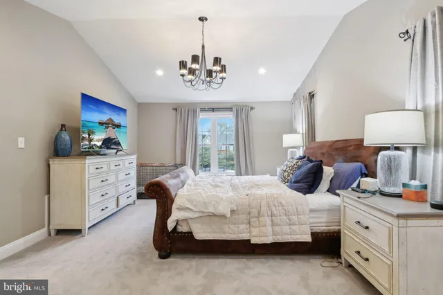 a bedroom with a bed chandelier dresser and a window