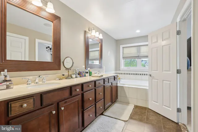 a bathroom with a tub a sink double vanity and a mirror