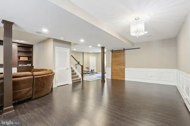 a view of an empty room with wooden floor and kitchen view