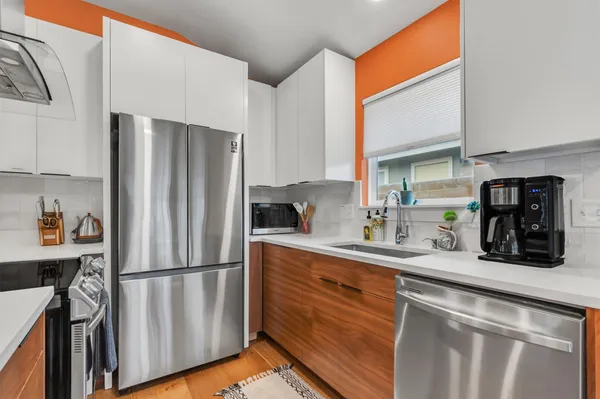 a kitchen with stainless steel appliances kitchen island granite countertop a refrigerator a stove and a sink with wooden floor