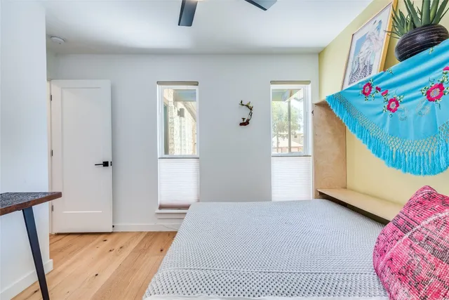 a view of an empty room with window and hardwood floor