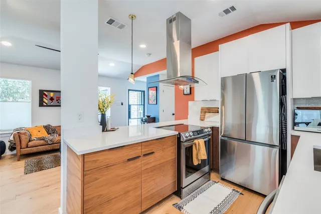 a kitchen with stainless steel appliances granite countertop a refrigerator a sink dishwasher a stove and a refrigerator with wooden floor