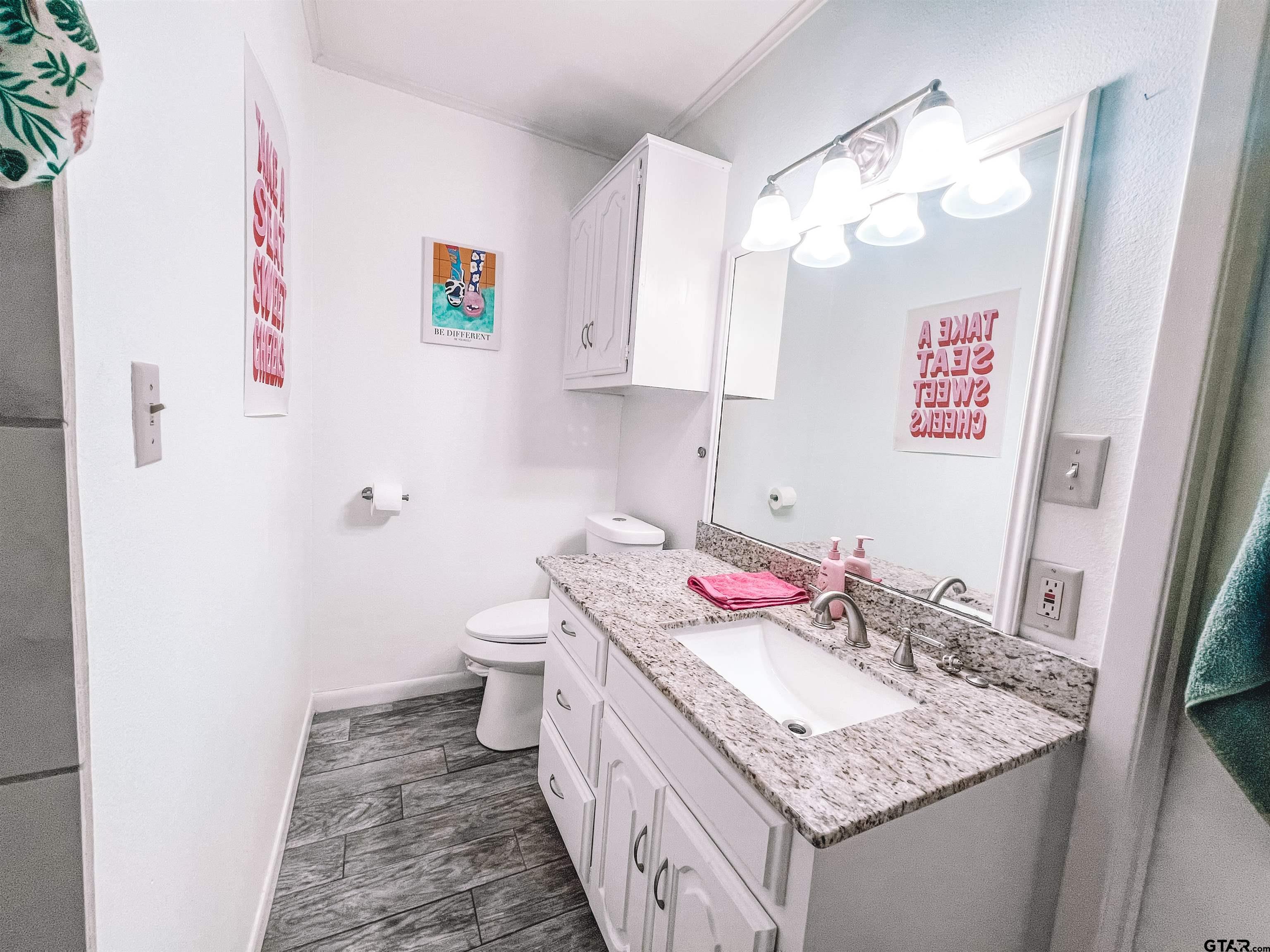 648 Daingerfield Street Pittsburg, TX 75686 - Photo 20 of 27 a bathroom with a granite countertop sink and a mirror