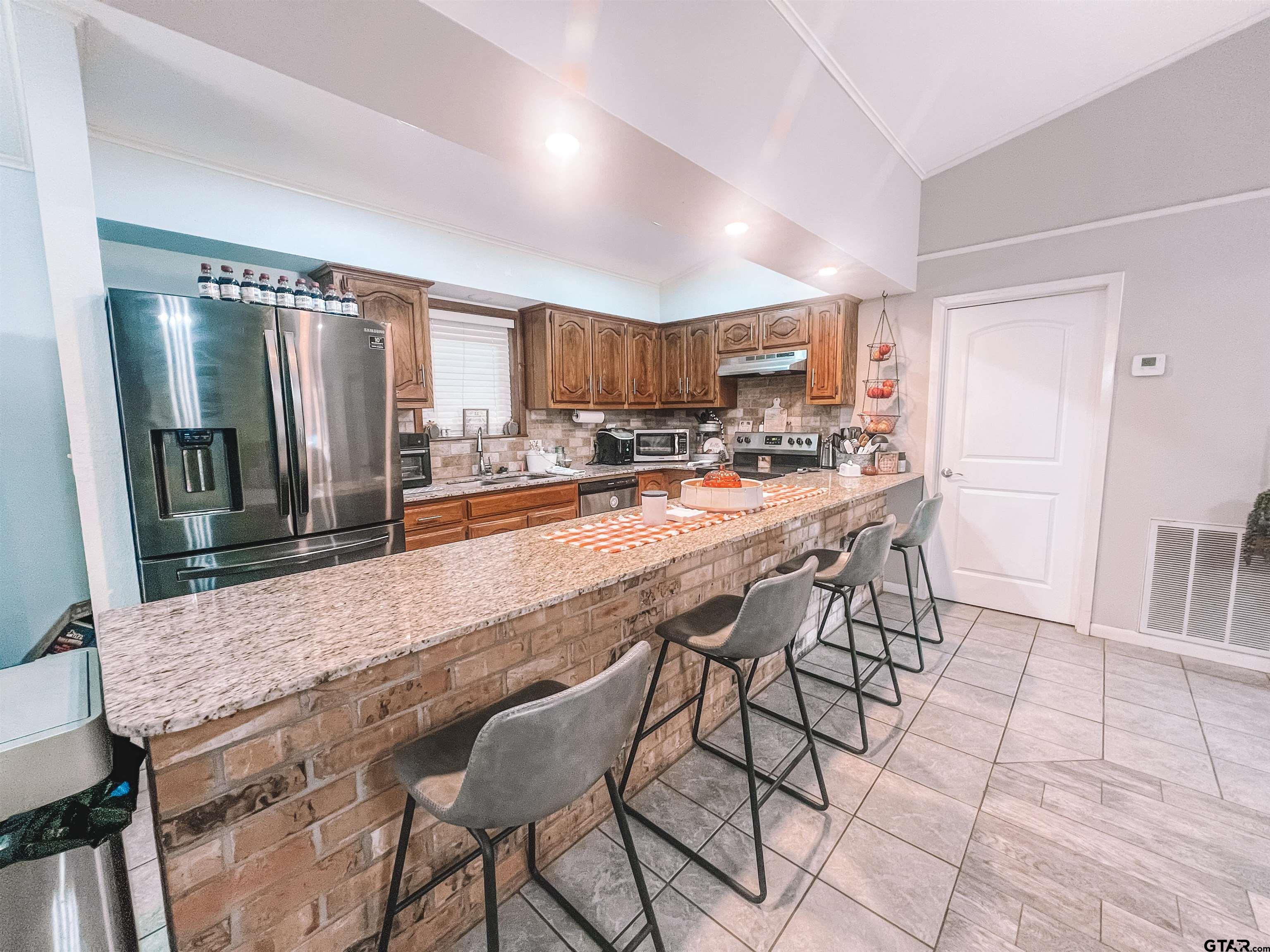 648 Daingerfield Street Pittsburg, TX 75686 - Photo 9 of 27 a dining hall with stainless steel appliances kitchen island granite countertop a table chairs and a refrigerator