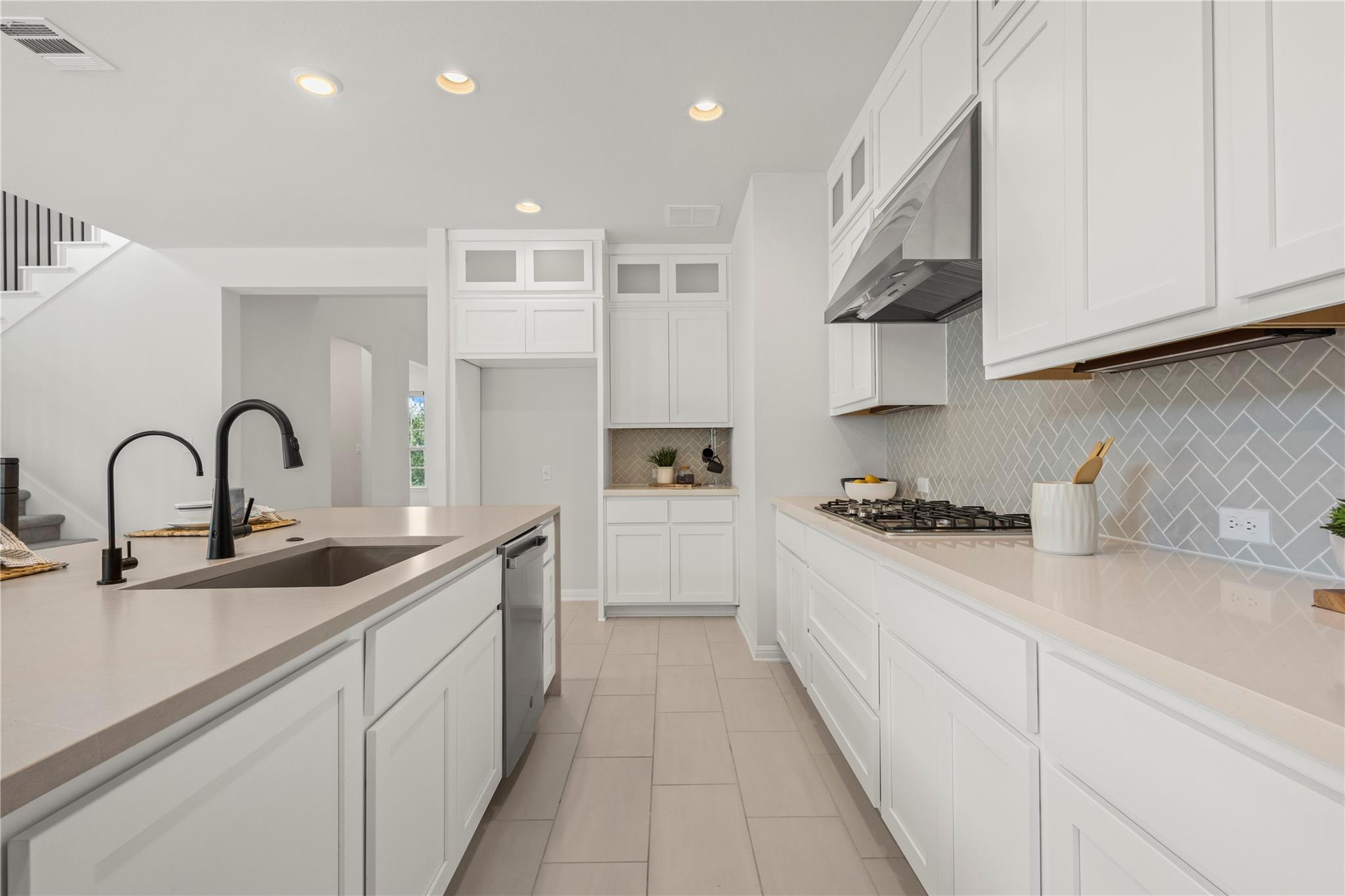 1128 Villa Rialto View Leander, TX 78641 - Photo 16 of 40 Kitchen with glass fronted cabinets, recessed lighting, white cabinets, and decorative backsplash