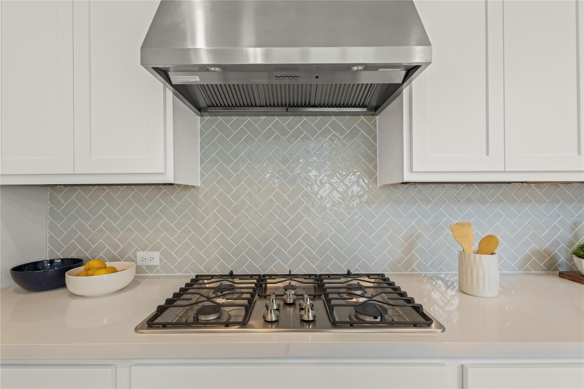 1128 Villa Rialto View Leander, TX 78641 - Photo 17 of 40 Kitchen featuring ventilation hood, stainless steel gas stovetop, white cabinetry, and tasteful backsplash