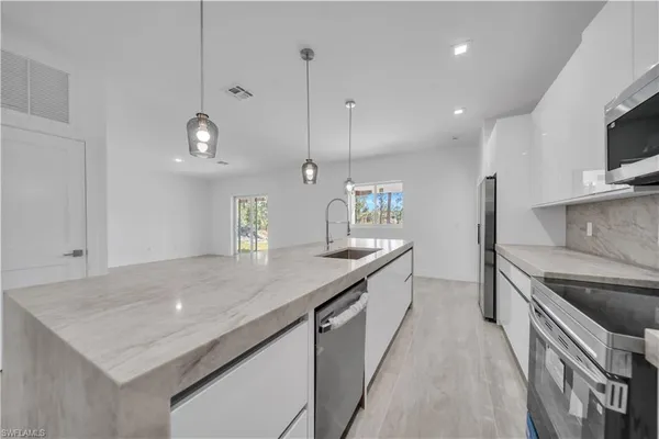 a kitchen with kitchen island a sink counter top space appliances and cabinets