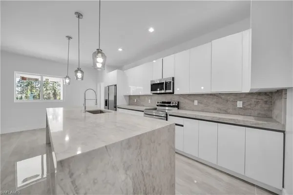 a kitchen with stainless steel appliances granite countertop a sink a stove and a refrigerator