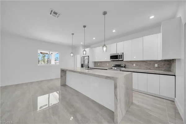 a kitchen with kitchen island white cabinets appliances and a chandelier
