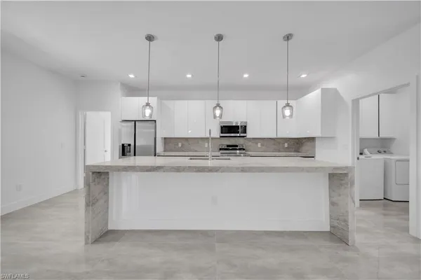 a large kitchen with kitchen island a stove a sink a center island and cabinets