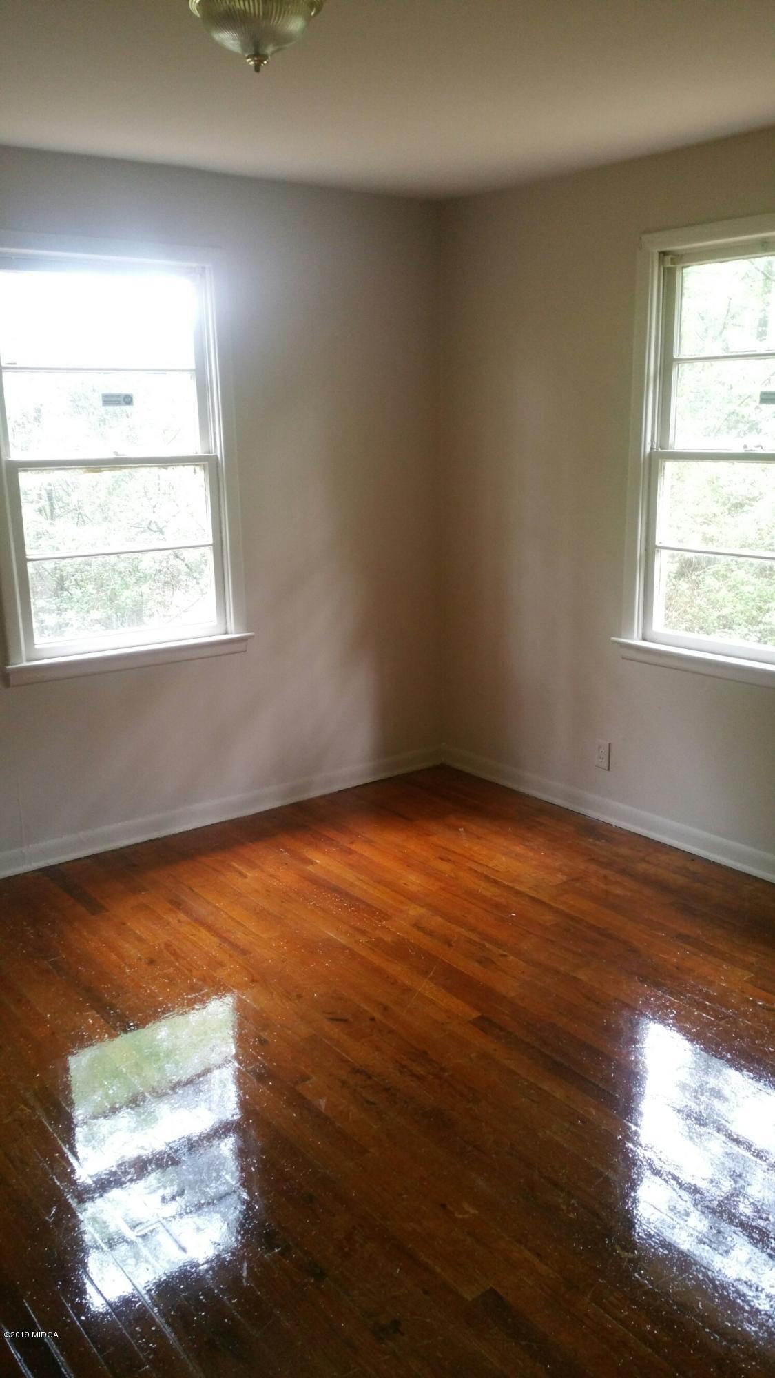 4843 Brookhaven Road Macon, GA 31206 - Photo 6 of 7 an empty room with wooden floor and windows