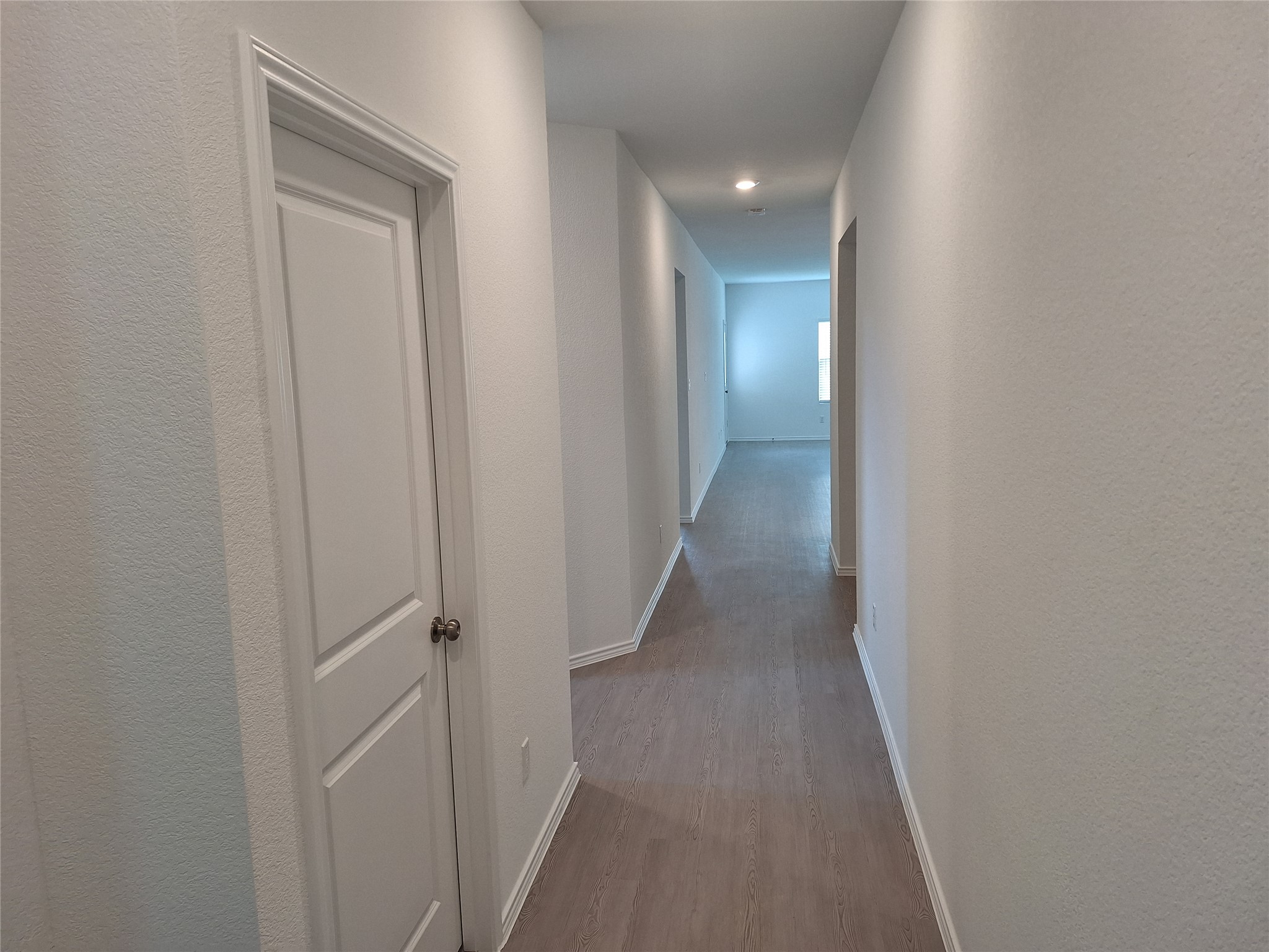 18001 Prairie Falcon Way Pflugerville, TX 78660 - Photo 4 of 38 Hallway featuring neutral wall paint, recessed lighting, wood-finish flooring, white trim, and a two-panel interior door with brushed nickel hardware