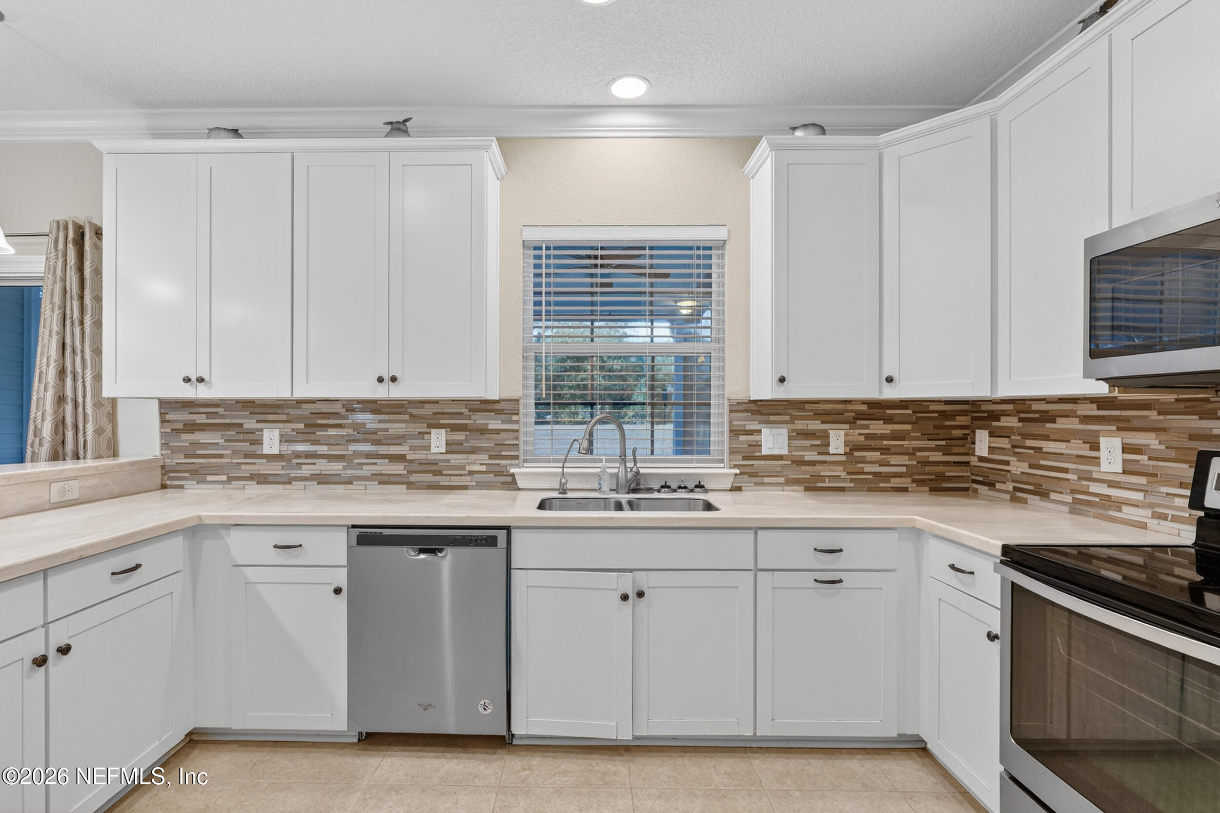 13576 Dunn Creek Road Jacksonville, FL 32218 - Photo 23 of 54 a kitchen with white cabinets appliances a sink and a window