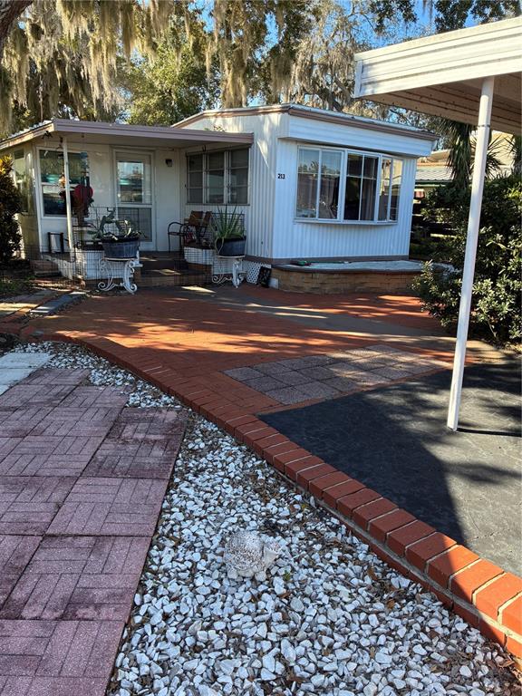 3896 Picciola Road, Unit 213 Fruitland Park, FL 34731 - Photo 1 of 12 a front view of house with yard outdoor seating and covered with trees