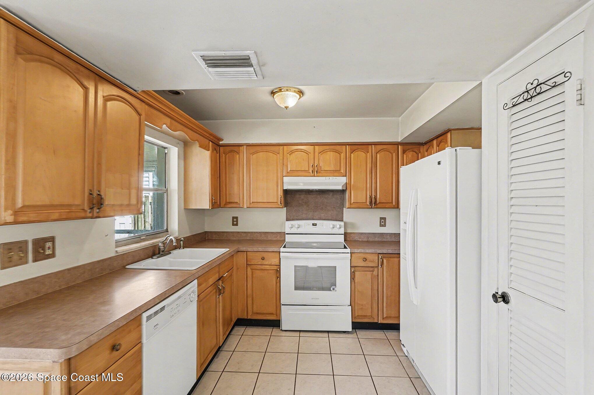3205 Dade Circle Northeast Palm Bay, FL 32905 - Photo 11 of 35 a kitchen with a sink cabinets stainless steel appliances and a window