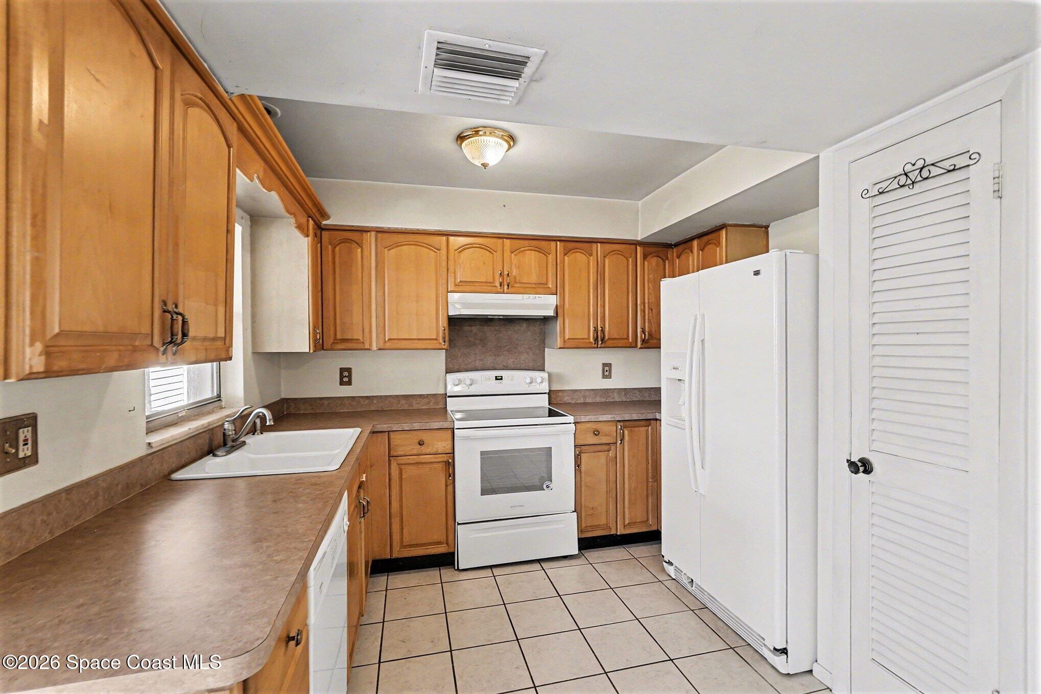 3205 Dade Circle Northeast Palm Bay, FL 32905 - Photo 12 of 35 a kitchen with a refrigerator a stove top oven a sink and cabinets