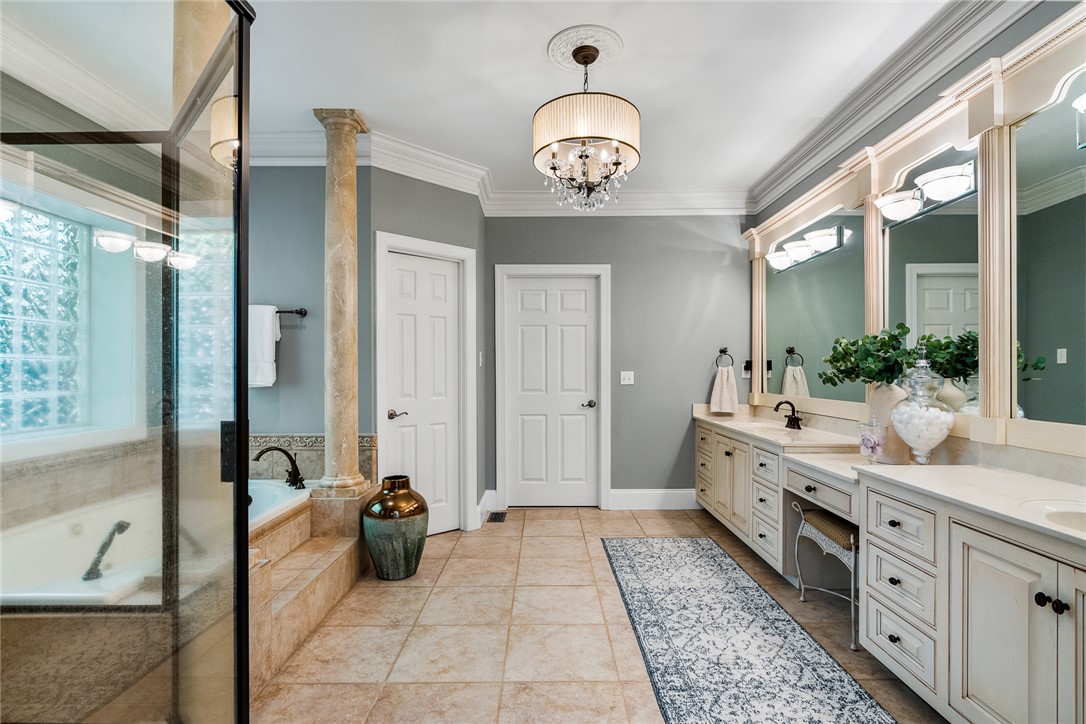 200 Graylyn Drive Anderson, SC 29621 - Photo 18 of 48 Elegant crown molding and a sophisticated chandelier elevate this spacious bathroom, featuring a grand soaking tub and dual vanities.
