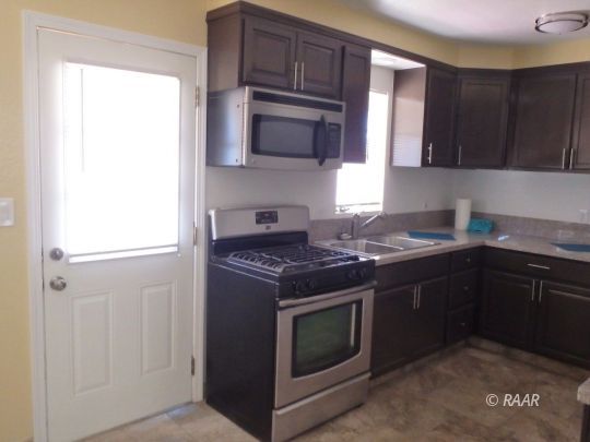 437 North Fairview Street Ridgecrest, CA 93555 - Photo 13 of 35 a kitchen with stainless steel appliances granite countertop a stove and a microwave