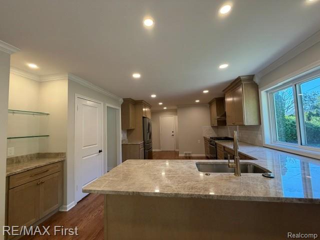 971 Canterbury Road Grosse Pointe, MI 48236 - Photo 15 of 30 Kitchen featuring recessed lighting, a built-in beverage station with glass shelving, wood-finish cabinetry, a large kitchen island with an undermount sink, and stone countertops
