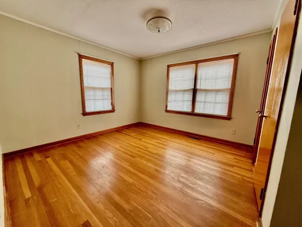 a view of an empty room with a window and wooden floor