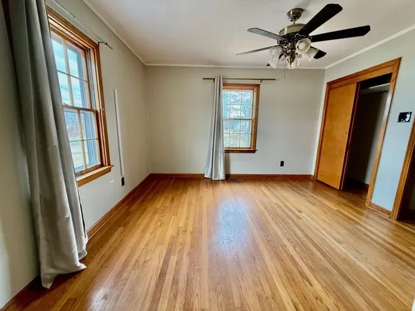an empty room with wooden floor and windows