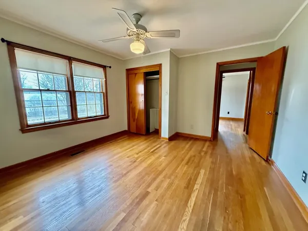 an empty room with wooden floor and windows