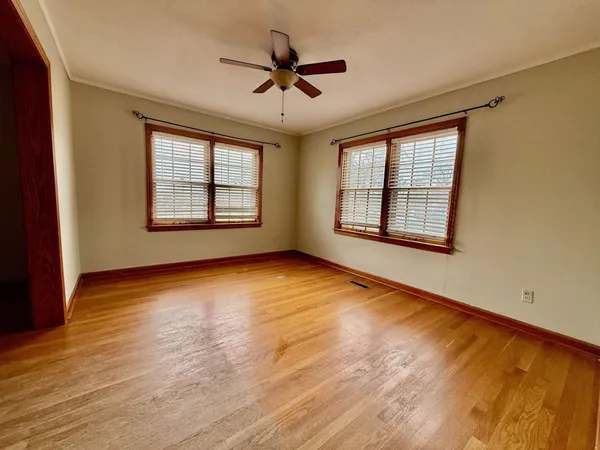 a view of an empty room with a window and wooden floor