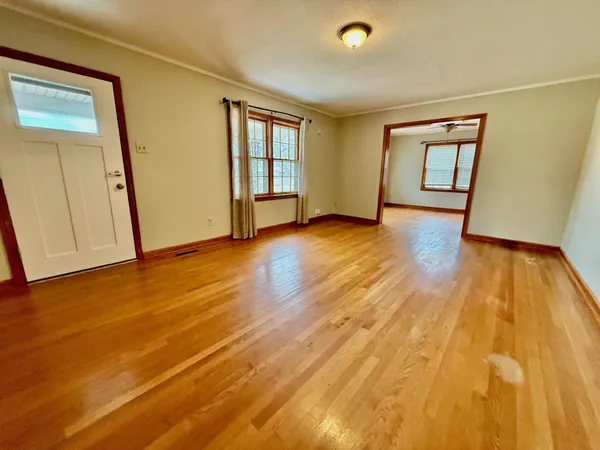 a view of an empty room with window and wooden floor