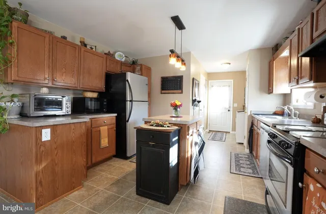 a kitchen with stainless steel appliances granite countertop a stove top oven a sink dishwasher a refrigerator and a dining table with wooden floor
