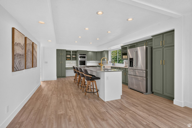 1979 Cave Hollow Way Bountiful, UT 84010 - Photo 10 of 59 Spacious kitchen featuring sage green cabinetry, stainless steel appliances, a large center island with seating, recessed lighting, and wood-finish flooring