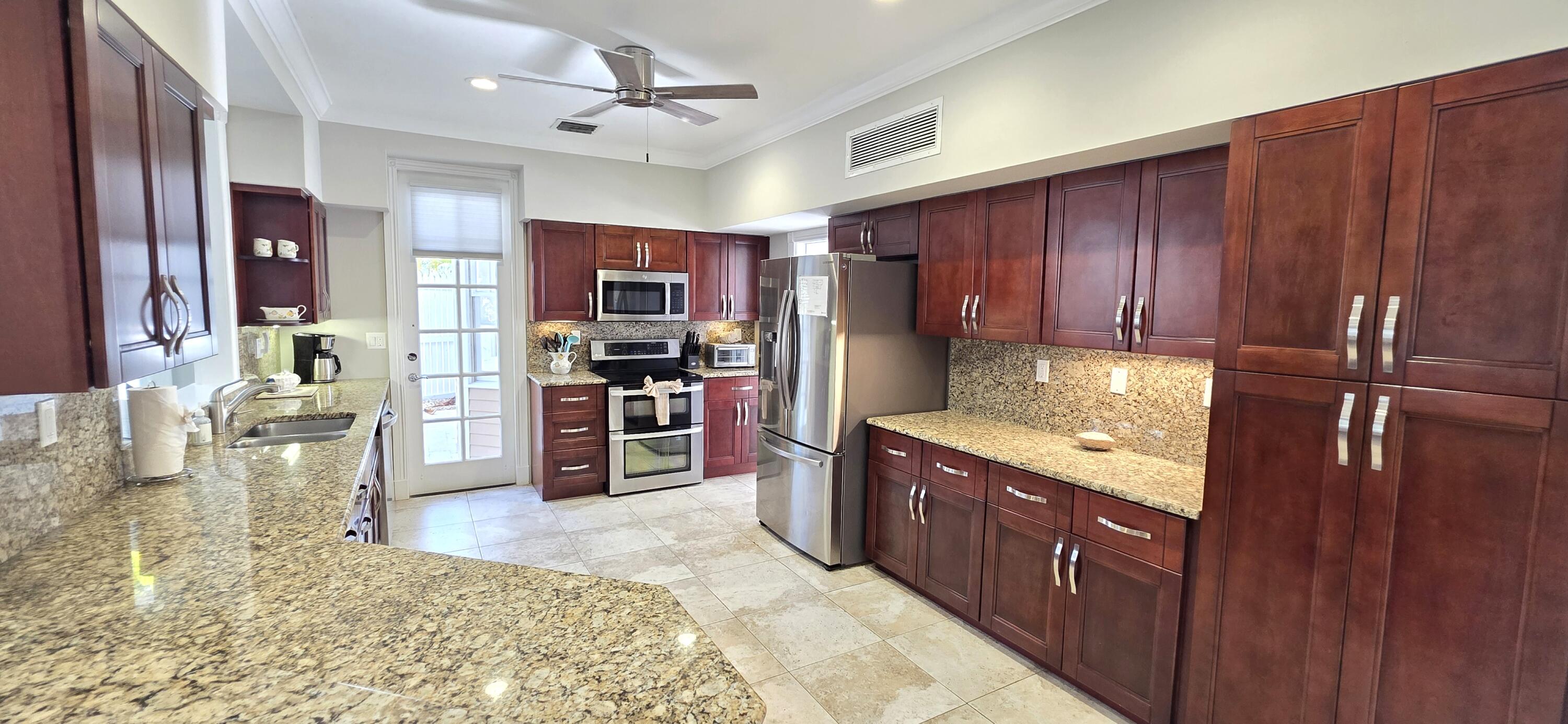 202 Admirals Lane Key West, FL 33040 - Photo 4 of 57 a kitchen with stainless steel appliances granite countertop a refrigerator a stove and a sink with wooden cabinets