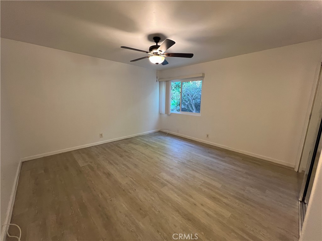 25091 La Cresta Drive, Unit B Dana Point, CA 92629 - Photo 12 of 30 an empty room with wooden floor chandelier fan and windows
