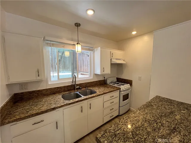a kitchen with granite countertop a stove a sink and a granite counter tops