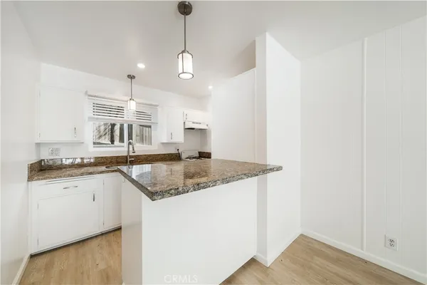 a kitchen with stainless steel appliances granite countertop a sink a stove and a wooden floor