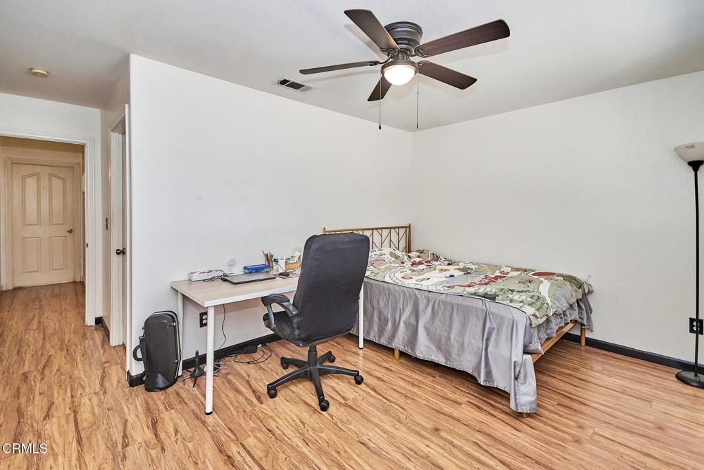9527 Riggins Road Phelan, CA 92371 - Photo 18 of 49 a bedroom with a bed a desk and chair with wooden floor
