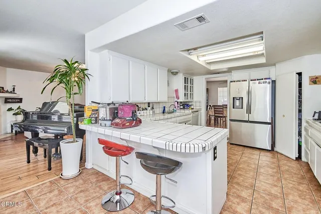 a kitchen with stainless steel appliances kitchen island granite countertop a refrigerator a stove a sink a dining table and chairs with wooden floor