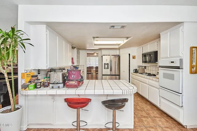 a kitchen with stainless steel appliances kitchen island granite countertop a refrigerator a stove and white cabinets