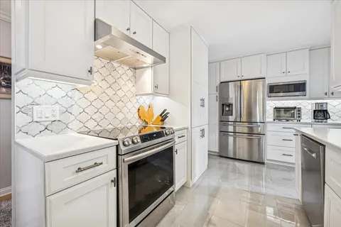 a kitchen with white cabinets and stainless steel appliances