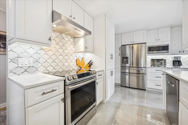 a kitchen with white cabinets and stainless steel appliances