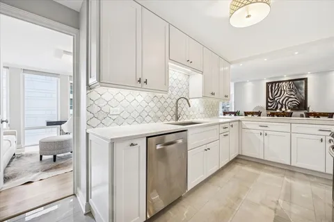 a kitchen with granite countertop a sink and white cabinets