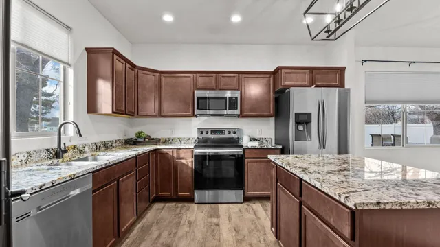 a kitchen with stainless steel appliances granite countertop a sink stove microwave and refrigerator