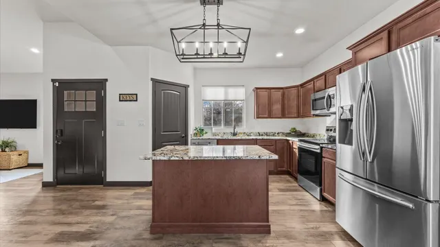 a kitchen with stainless steel appliances granite countertop a refrigerator a sink dishwasher a oven and a refrigerator with wooden floor