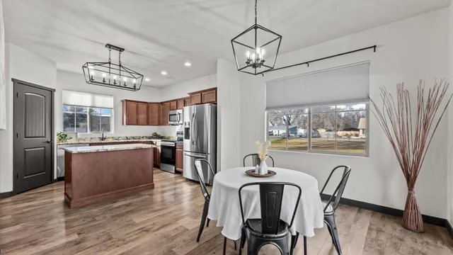 a kitchen with stainless steel appliances kitchen island granite countertop a refrigerator a stove a kitchen island with a dining table and wooden floor