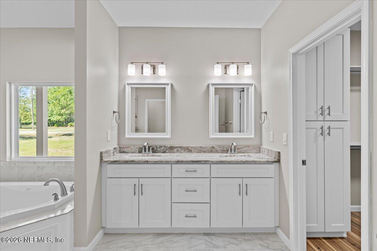 2462 Viola Street Middleburg, FL 32068 - Photo 18 of 61 a spacious bathroom with double vanity a mirror a bathtub and a shower