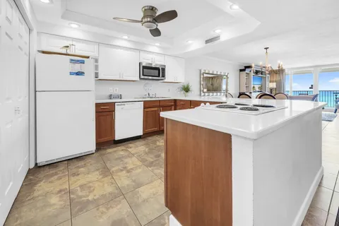 a kitchen with stainless steel appliances granite countertop a sink a stove a refrigerator cabinets a dining table and chairs