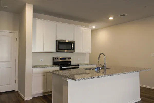 a kitchen with a sink a microwave and cabinets