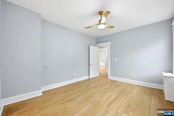 a view of an empty room with chandelier fan and wooden floor