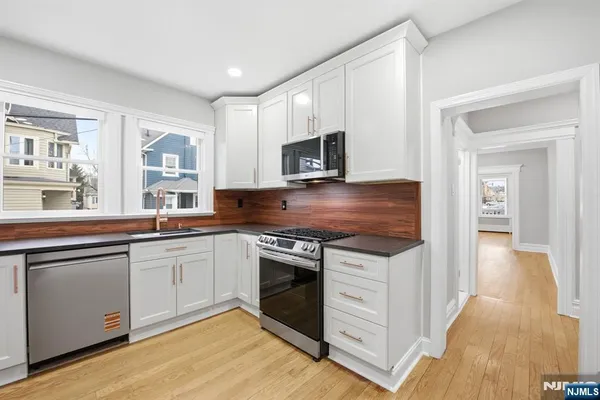 a kitchen with granite countertop cabinets stainless steel appliances and a wooden floor
