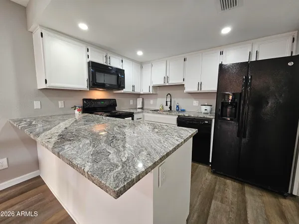 a kitchen with stainless steel appliances granite countertop a refrigerator a stove a sink a microwave and white cabinets