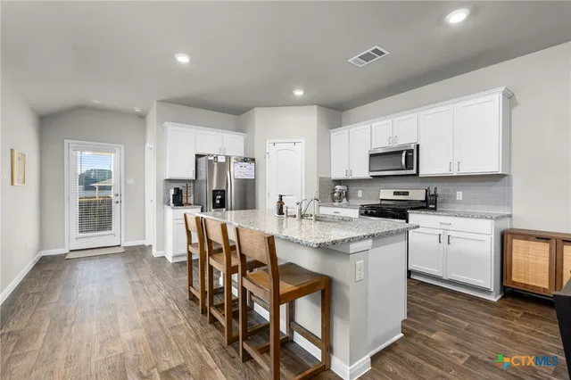 a kitchen with appliances a sink a counter top space and cabinets
